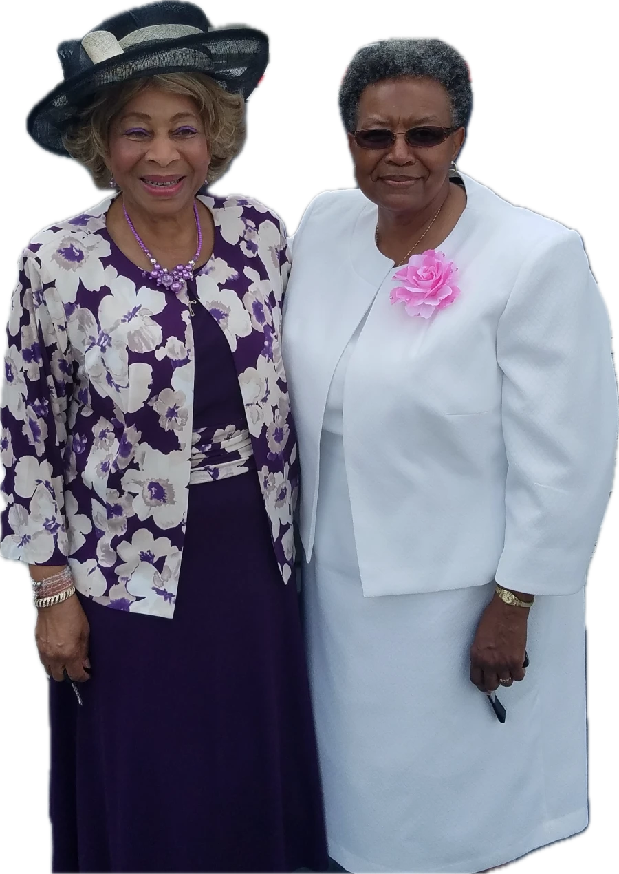 Dr. Meta Broadnax, wearing sunglasses and a white jacket with a pink rose brooch, with a friend.